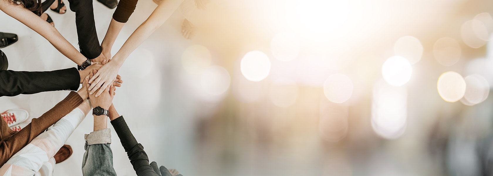 Mehrere H&auml;nde liegen &uuml;bereinander und symbolisieren Teamzusammenhalt.