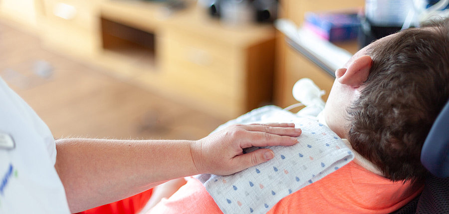 Die Hand einer Pflegekraft ruht auf einer intensivpflegebed&uuml;rftigen Person