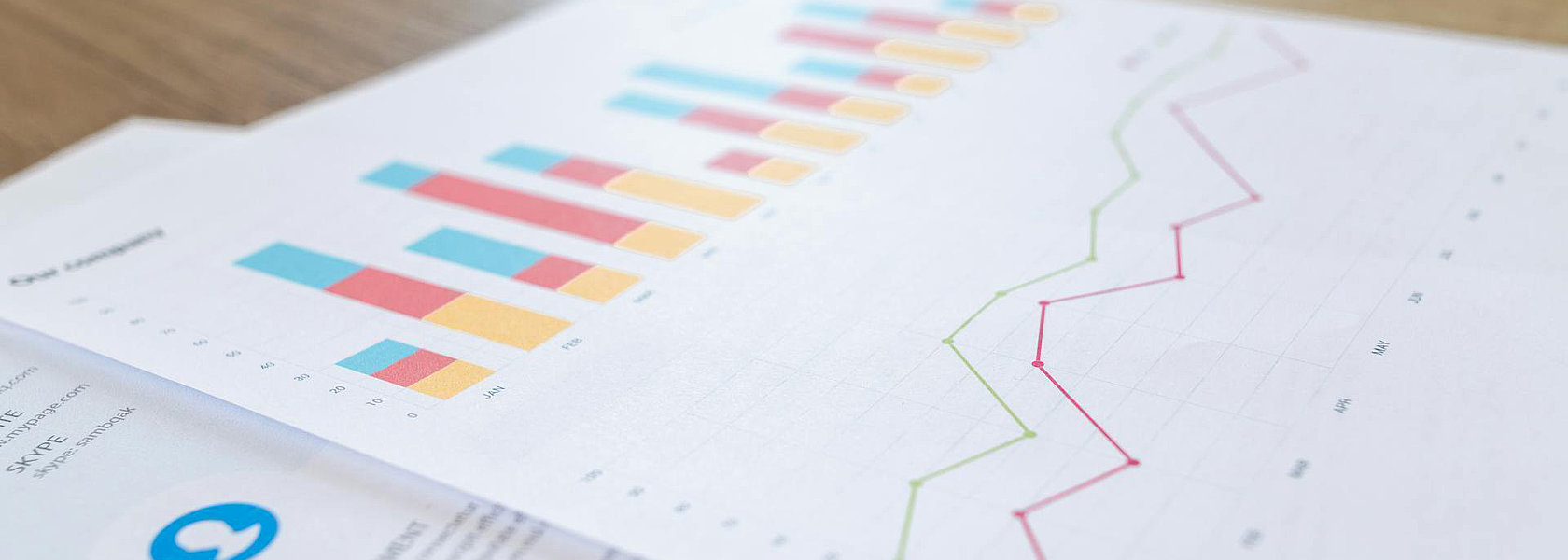 Ein gedruckter Jahresbericht mit bunten Balkendiagrammen und Liniendiagrammen liegt auf einem Holztisch. Die Grafiken zeigen statistische Auswertungen.