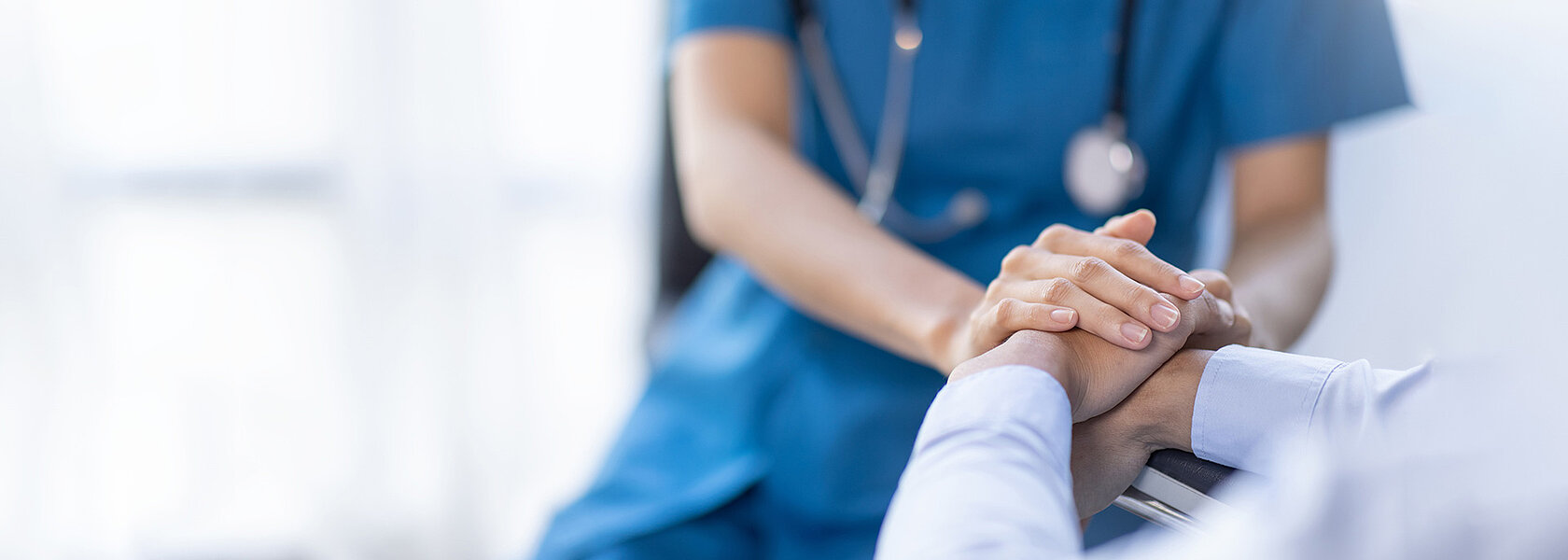 Eine Krankenschwester hält die Hand eines Patienten.